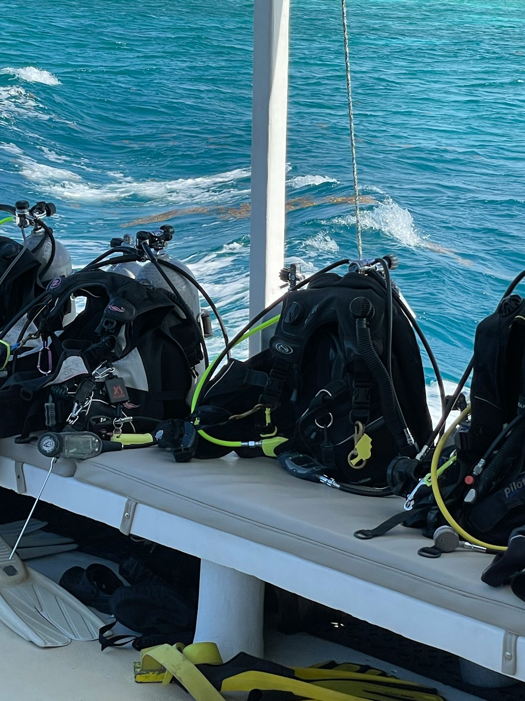Scuba gear neatly arranged on a boat bench near turquoise water.