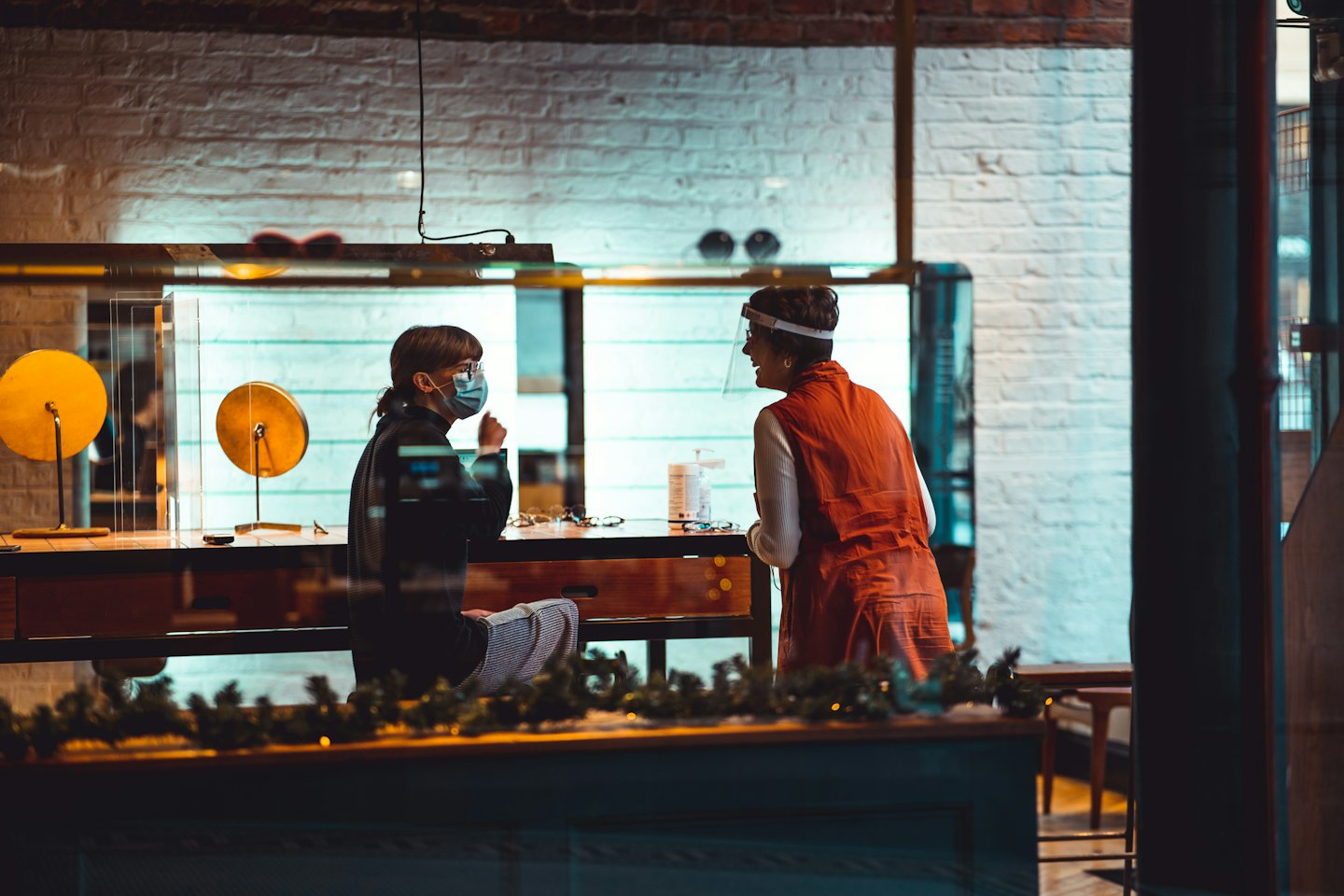 Customer and optician talk at counter in eyewear shop.