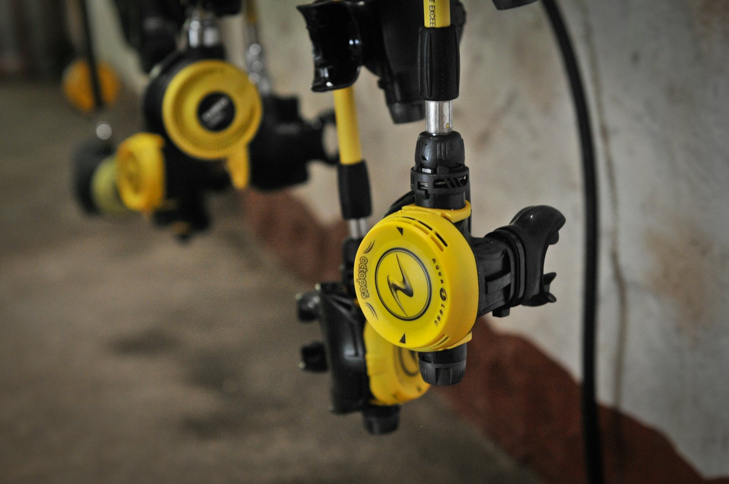 Yellow and black scuba diving regulators hang on a wall.